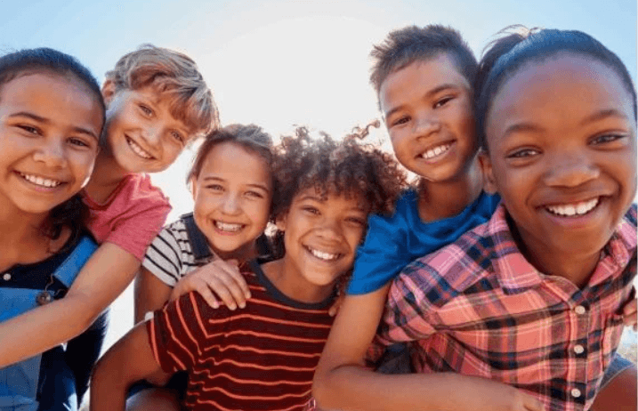 A photo of a group of children posing against a sunny sky